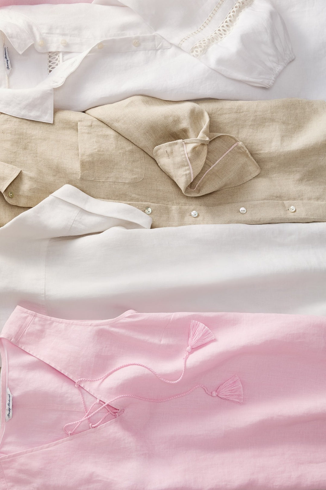 Stack of folded shirts in white, beige, and pink.