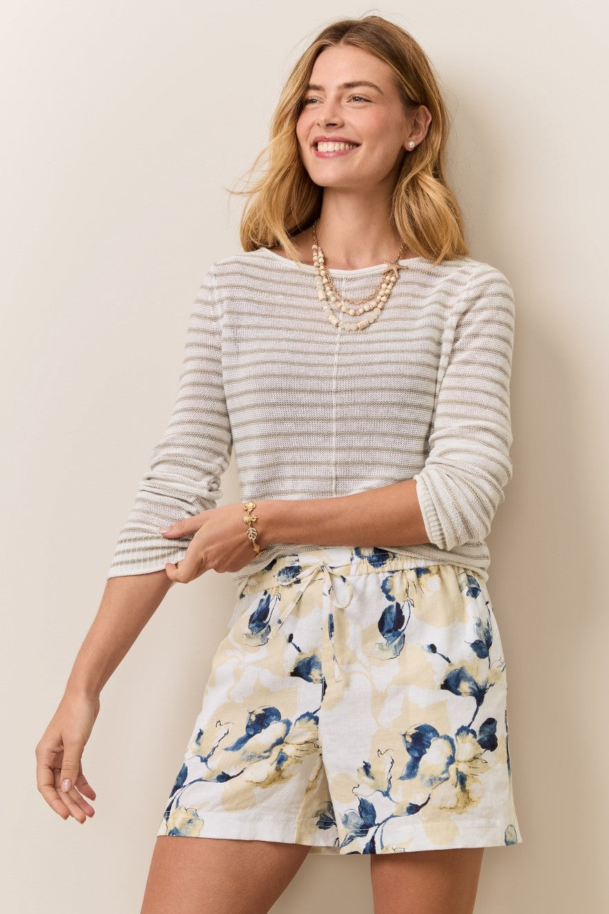 Woman wearing a Tommy Bahama striped sweater and floral shorts against a plain background